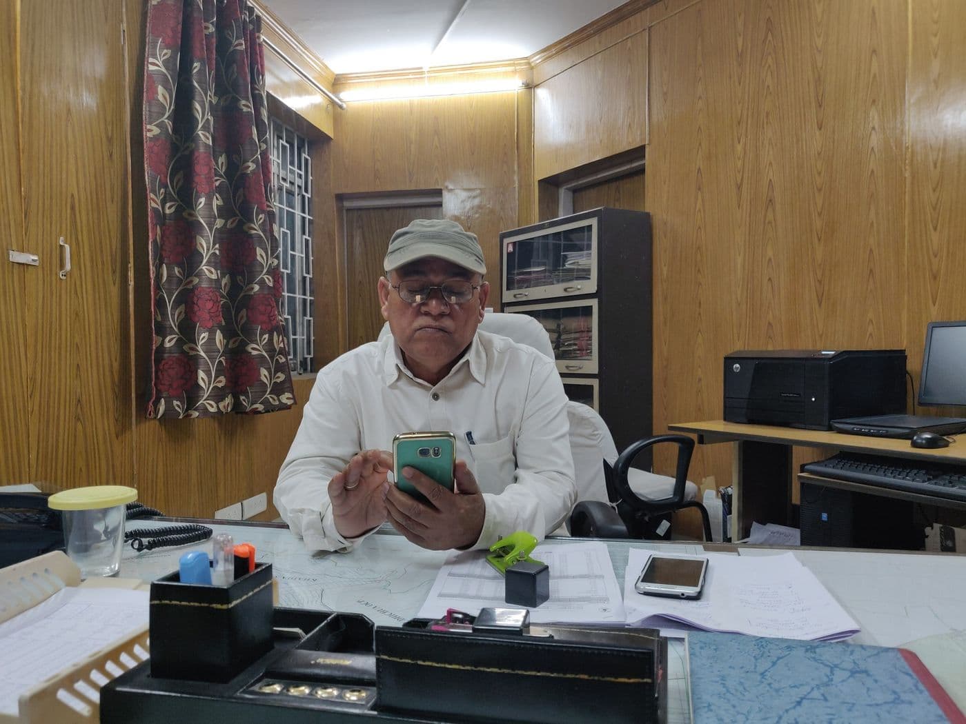 दफ़्तर की मेज़ पर खदान के नक़्शे फैले हुए, कुर्सी पर बैठे हुए